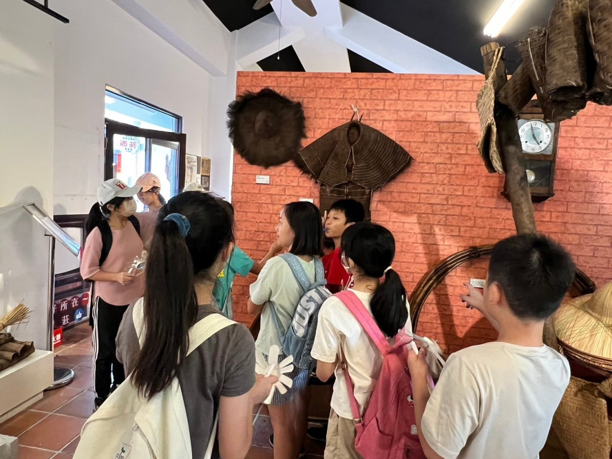 學生好奇看著牆上的簑衣可是雨衣 0